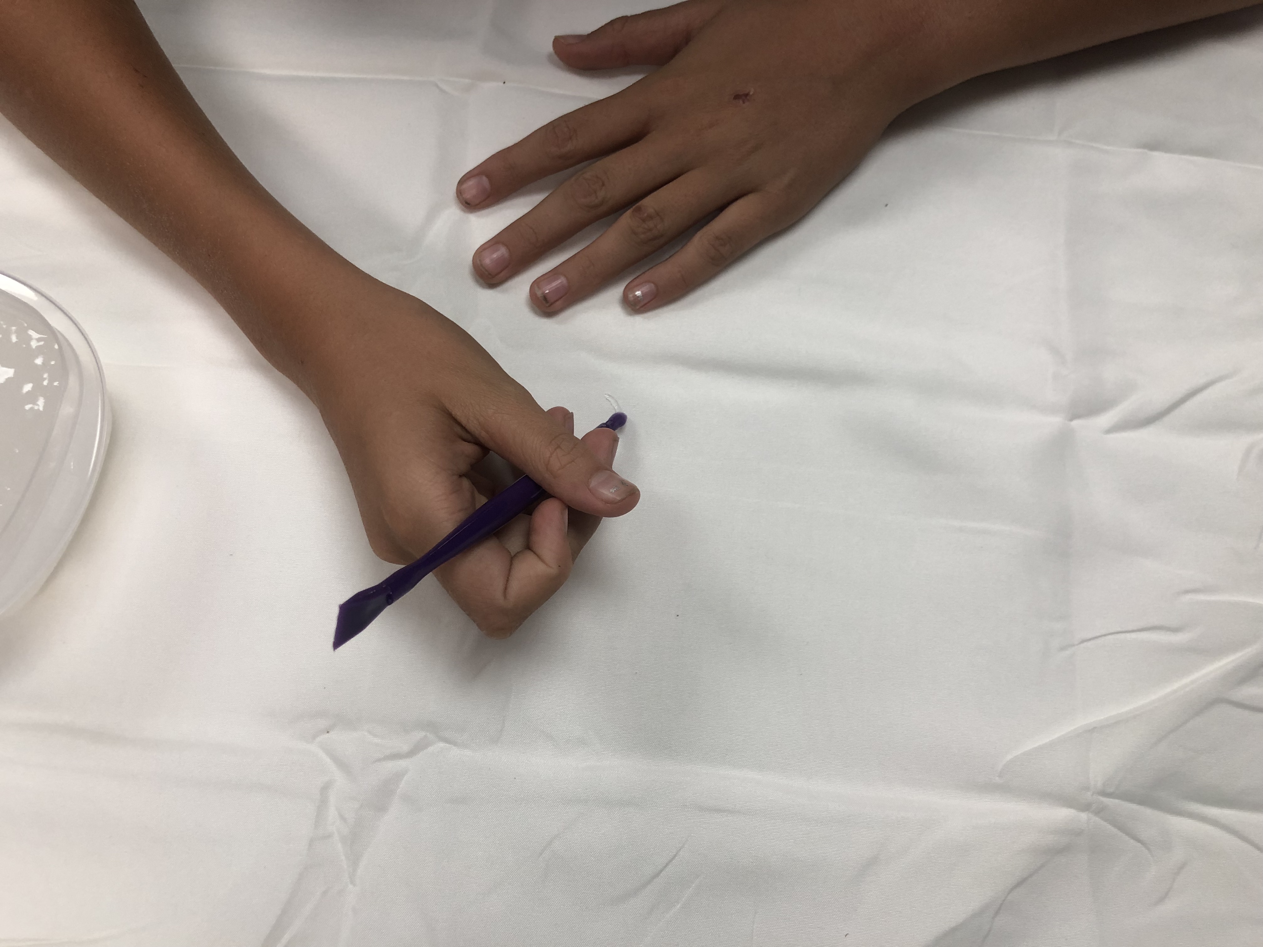 Hands using cassava flour starch paste to make patterns on fabric