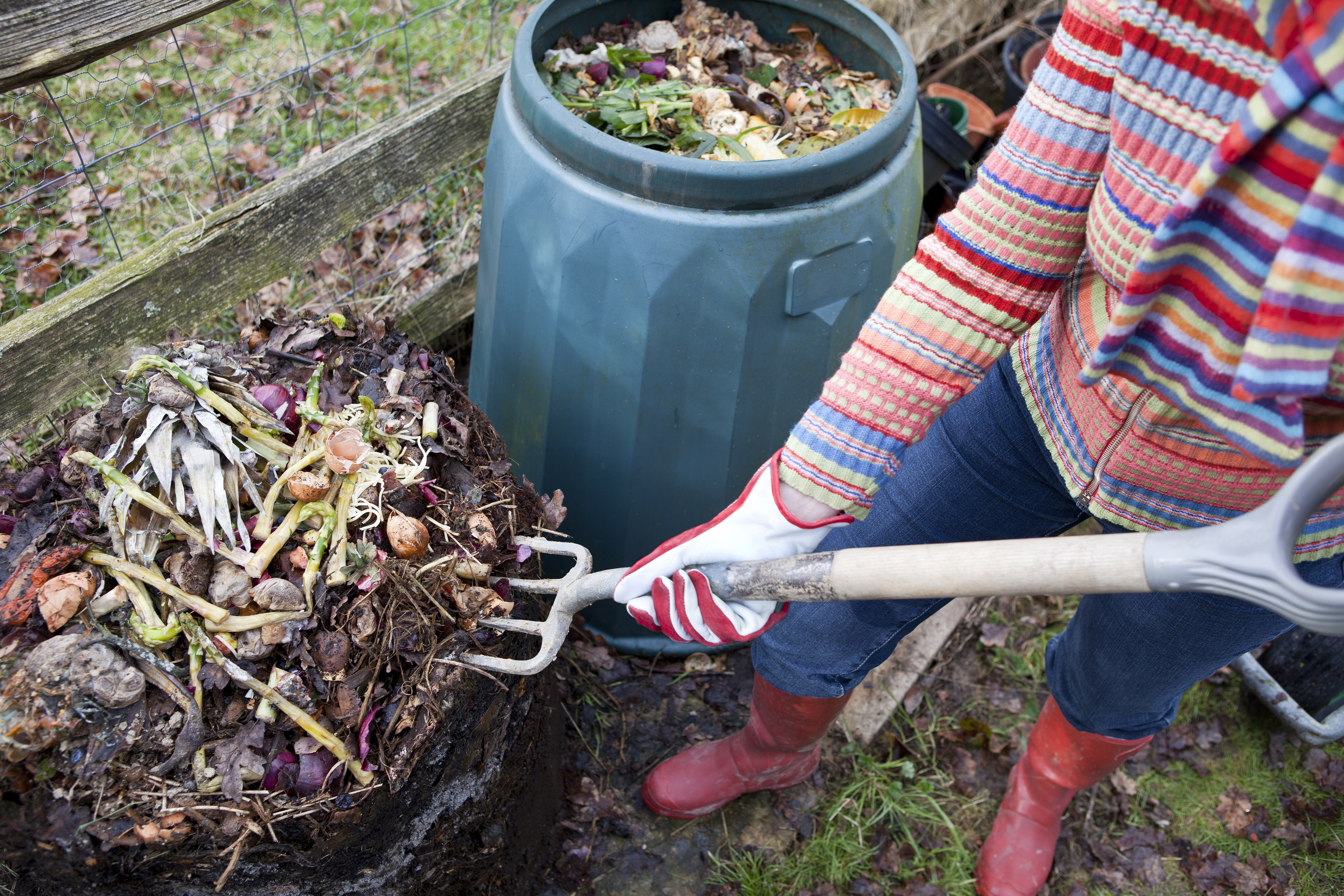 Woman moving composting materials with pitchfork