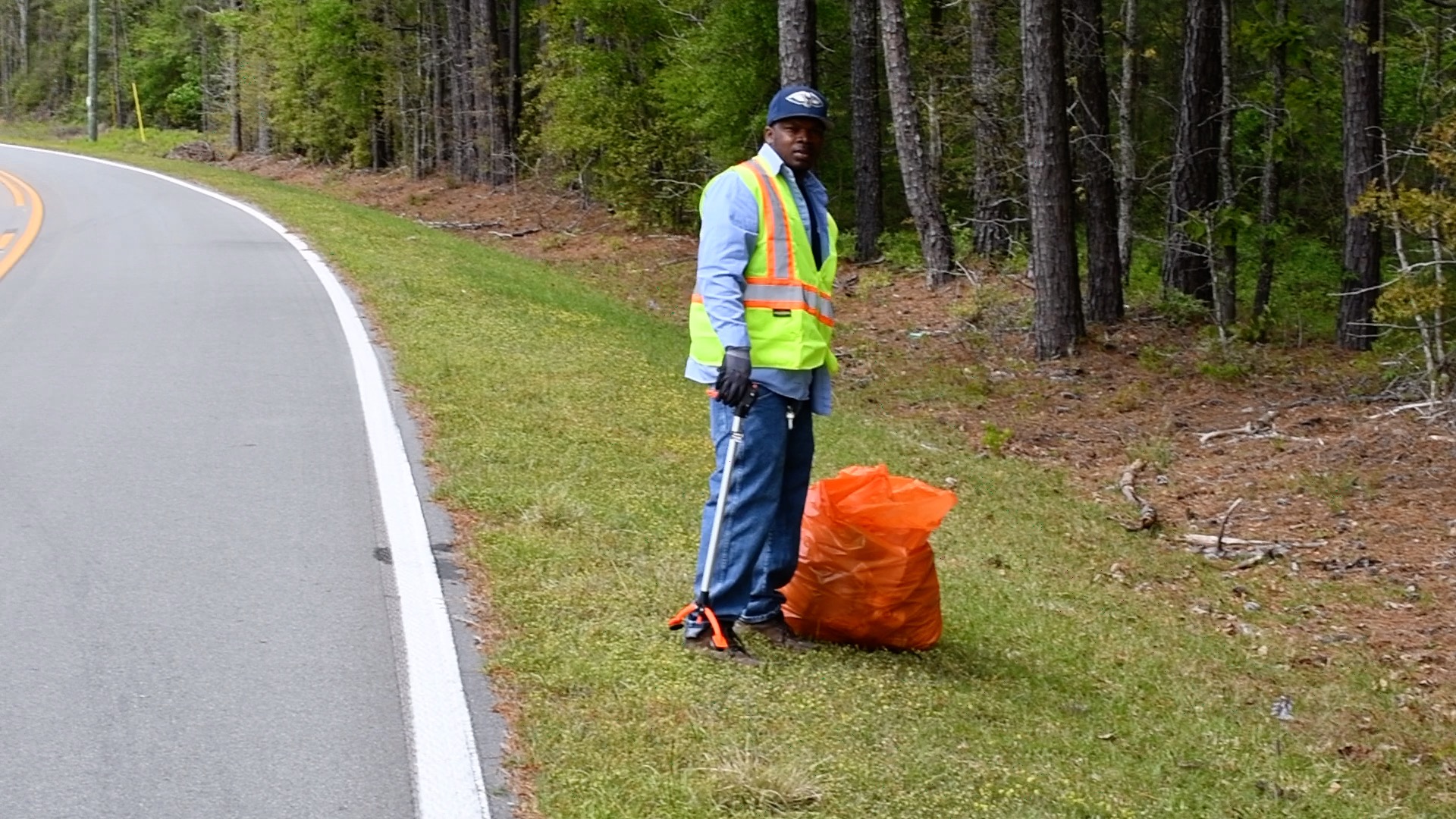 man picking up trash on side of road