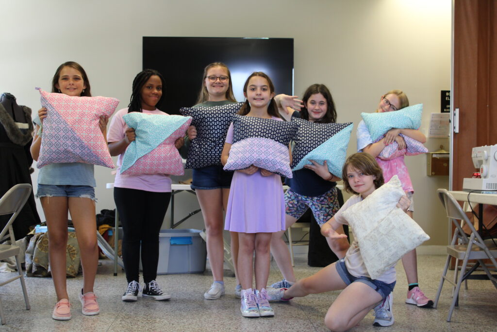 A group of children holding their finished pillow projects.