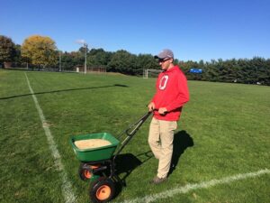 man spreading fertilizer on lawn