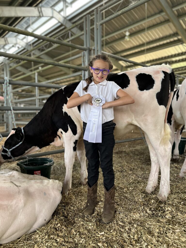 Yoshiko Clifton standing next to her dairy calf and holding her third place ribbon